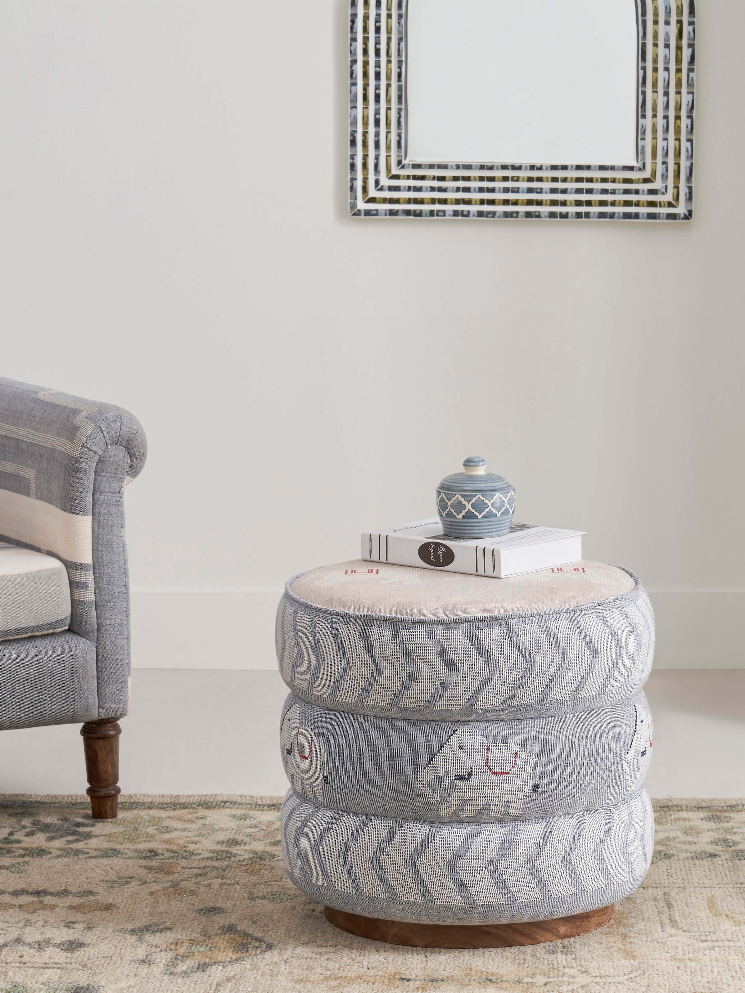 Side view of the Bawan Buti pouffe, highlighting the upholstery and the Sheesham wood frame