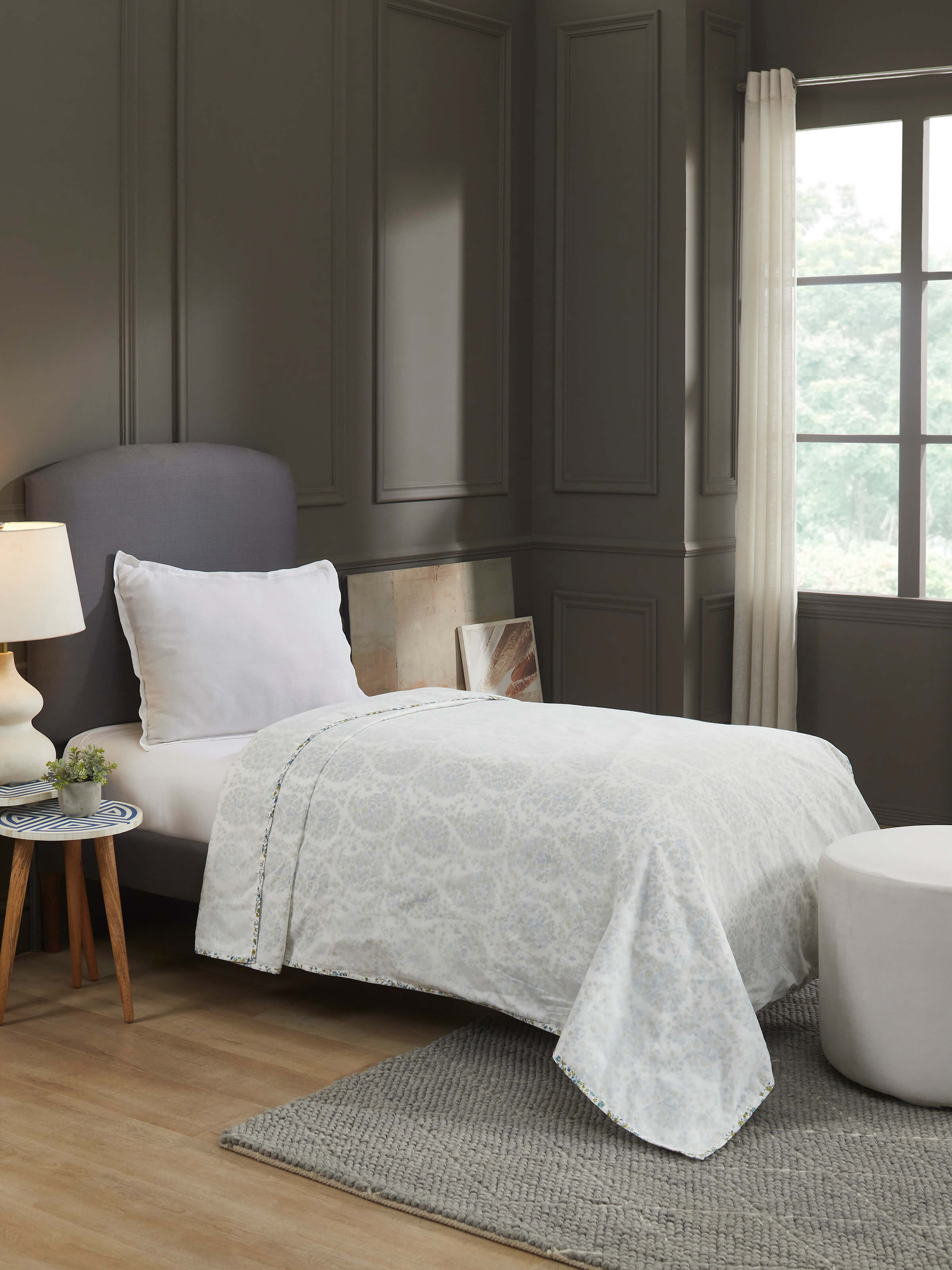 Lifestyle view of hand block printed blue dohar styled on a bed in bright natural light.