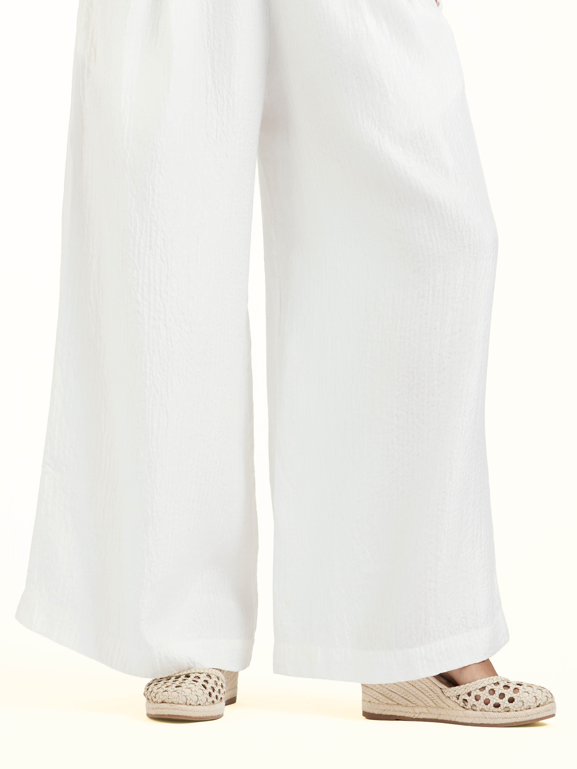 Detail view of ivory quilted silk pants showing fabric texture and stitch details