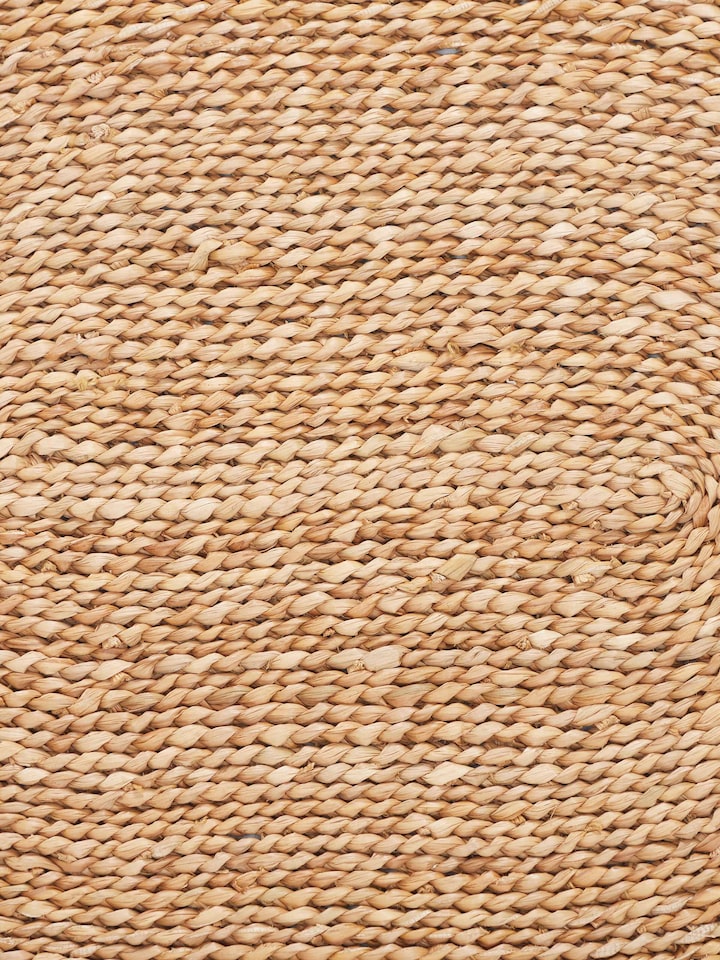 Top-down view of Vritti brown solid oval natural fibre trivets showing the texture and natural material.