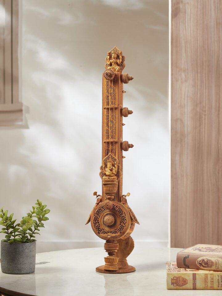 Side view of carved sandalwood veena sculpture, highlighting the detailed wooden carving and artistic form.