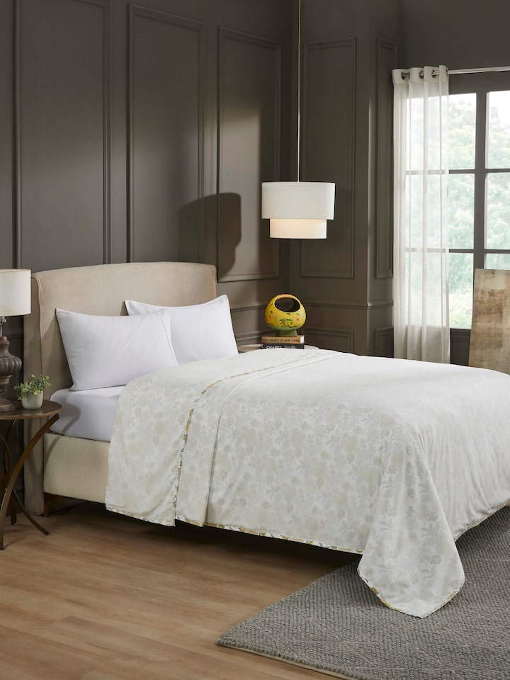 Bed styled with yellow floral Sanganeri dohar – cotton double-layered quilt.