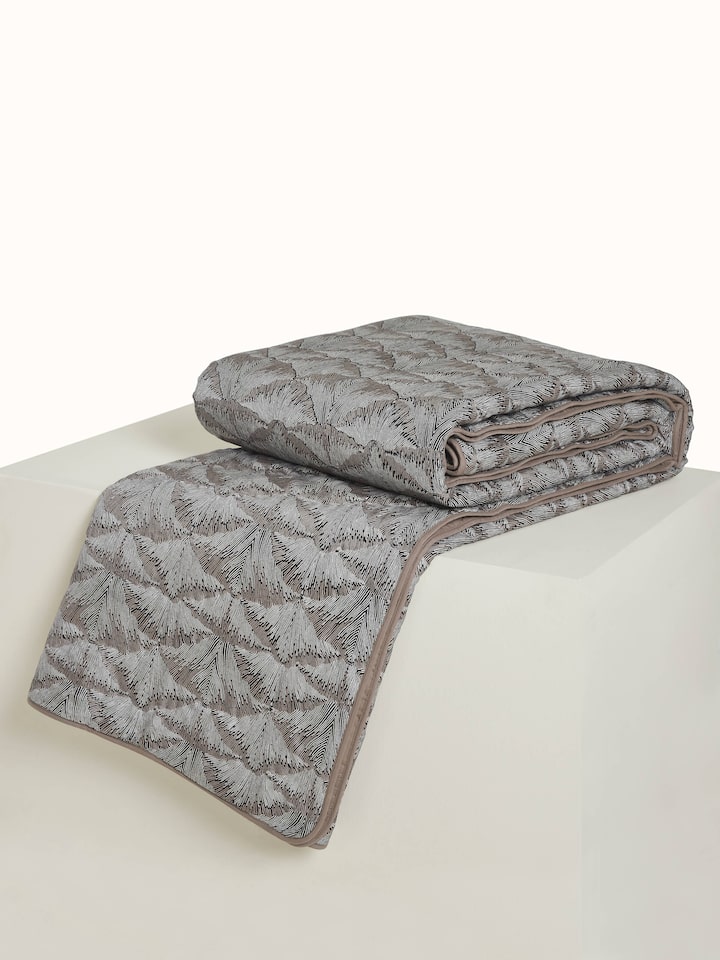 Angled view showing the intricate Sanganeri block print on Parvat brown silk quilt.