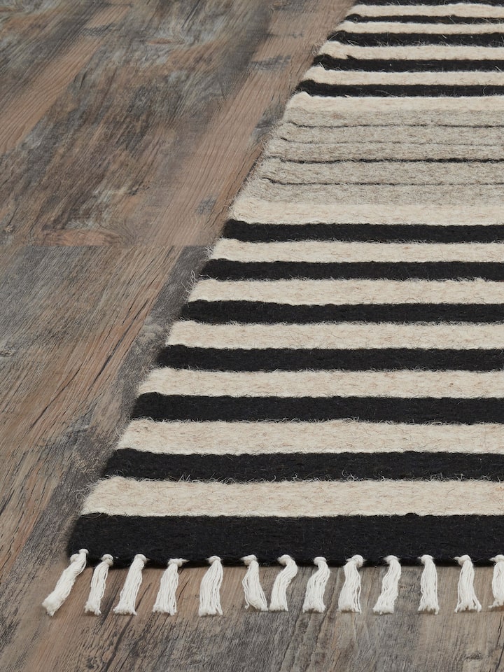 Angled view of Nomad Stripes Black Beige Jawaja Wool & Cotton Handloom Dhurrie (3x5 ft) displaying the dhurrie’s size and stripe design