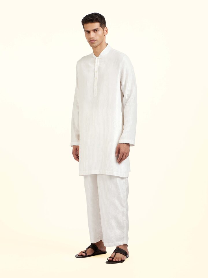 Side view of white straight quilted tulip pants showing tapered silhouette and quilted texture