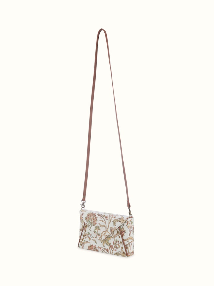 Angled close-up of hand block printed textile and leather detailing on mustard sling bag