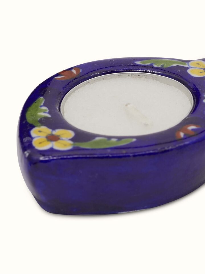 Detail close-up of blue pottery tea light holder showing glaze and artwork