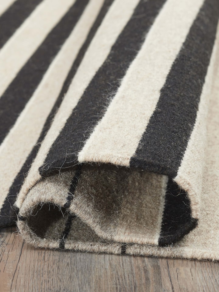 Side view of Nomad Stripes Black Beige Jawaja Wool & Cotton Handloom Dhurrie (3x5 ft) emphasizing its durability and handloom craftsmanship