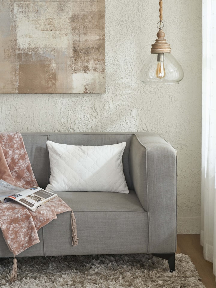 Shivranjini beige solid textured cotton razai embroidered lumbar cushion cover styled on sofa – Swadesh