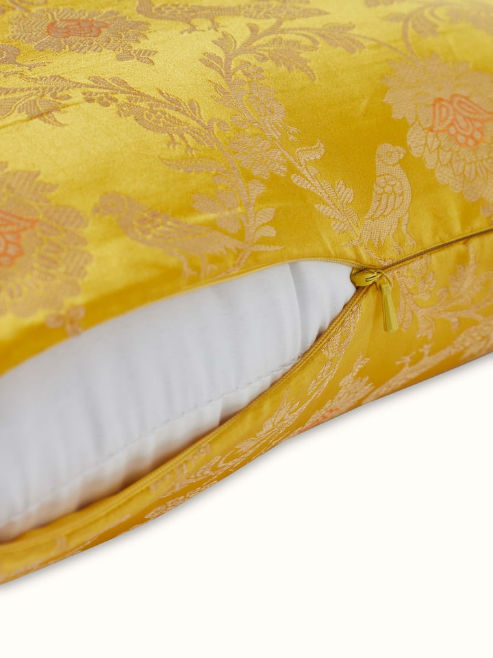 Angled view of Awadh Yellow Jaal Banarasi Silk Cushion Cover, displaying the intricate weaving and golden accents.