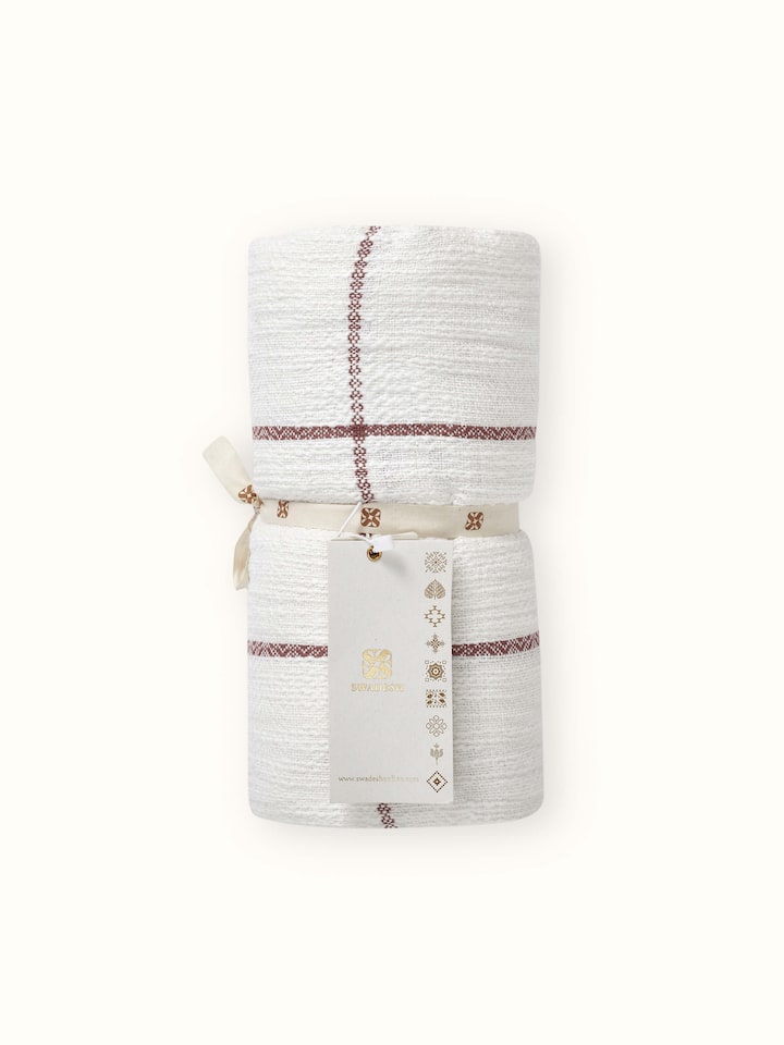 Angled detail capturing warmth and subtle texture of blush handloom throw.