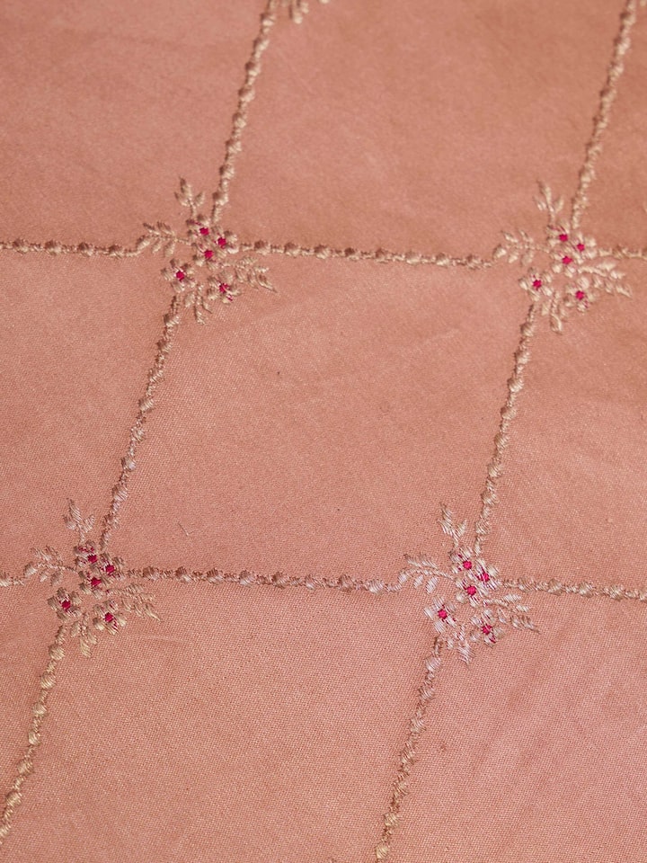 Angled display of Mandana peach silk brocade table mats showcasing fine craftsmanship.
