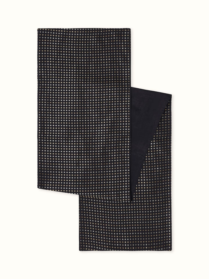 Angled view of black silk Banarasi brocade table runner with golden motifs and handloom texture.