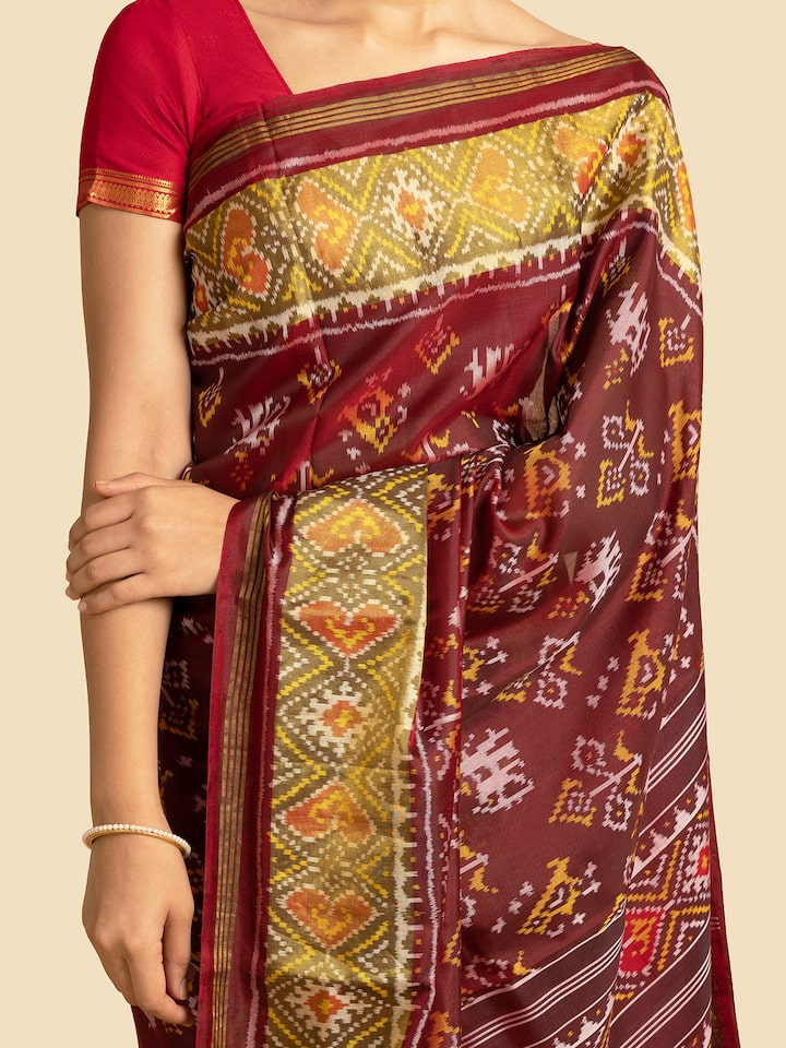 Detailed view of red silk patola saree’s draping style and intricate border work