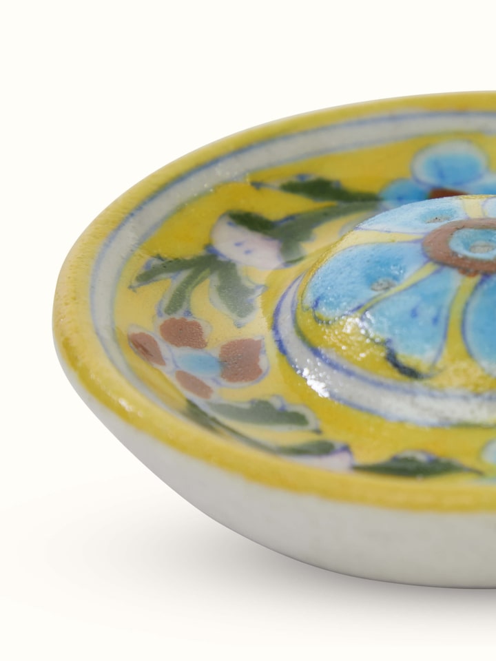 Detail close-up of ceramic floral incense stick holder showing painted design