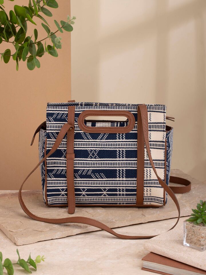 Woman carrying extra-weft sling bag with leather flap in a casual setting.