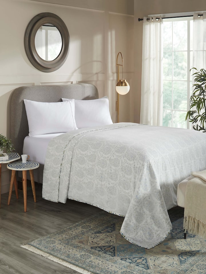 Styled bedroom shot with paisley cotton dohar laid over a bed.