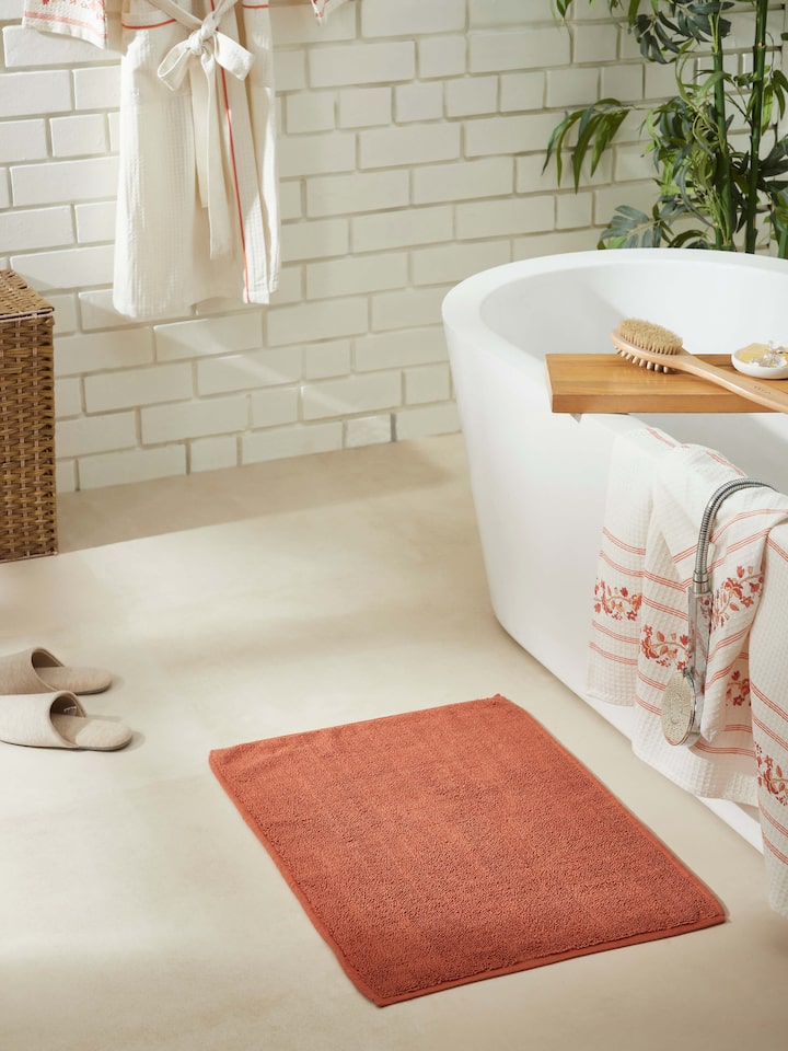 Rust cotton bath mat placed in bathroom setting