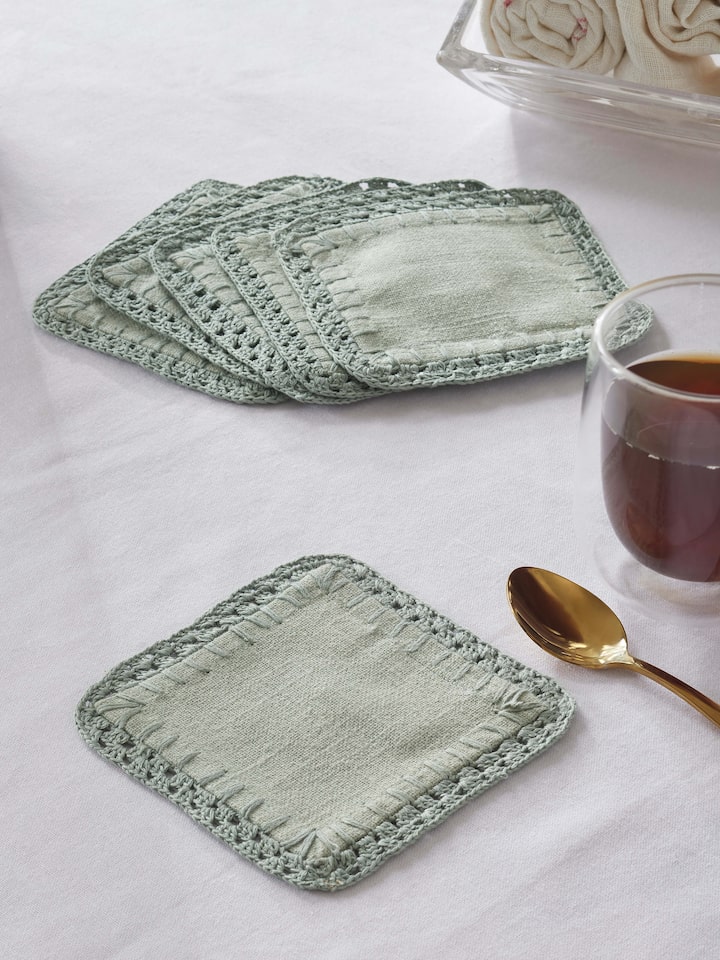 Nityam Light Green Cotton Slub Crochet Coaster styled on a table with a teacup and spoon