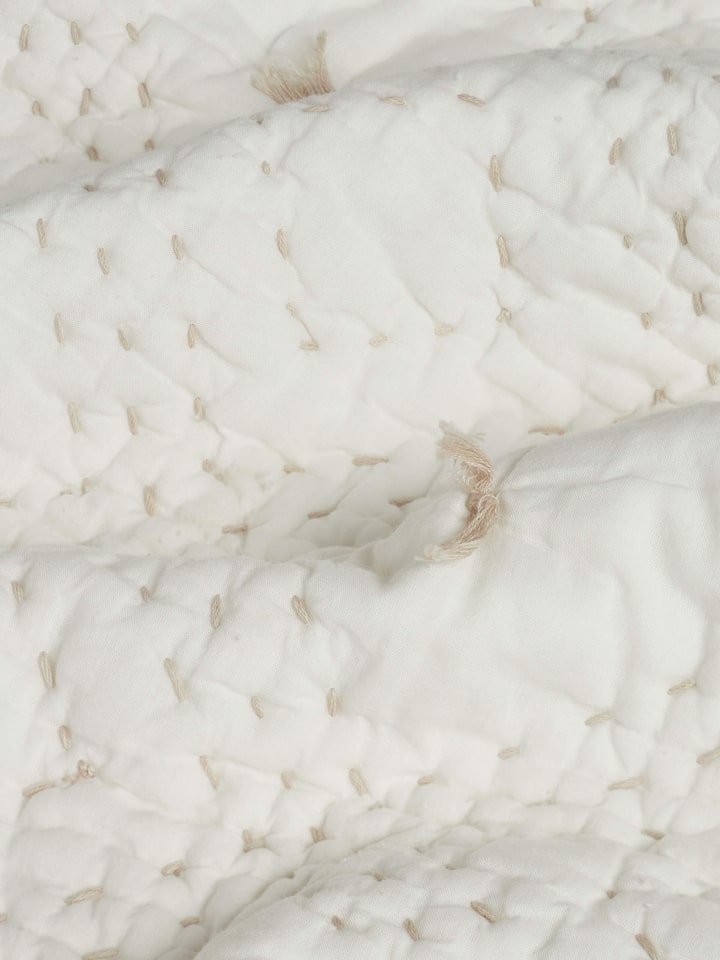 Nihar ivory diamond geo cotton razai embroidered double bedspread set (3 pcs) spread on a bed to showcase its complete look and design.