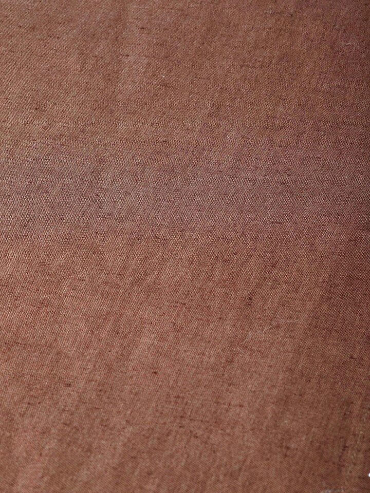 Close-up of hand embroidery and stitched border on brown table mat