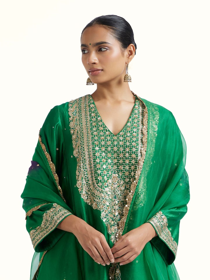 Angled view of emerald green silk hand embroidery kurta set highlighting embroidery work