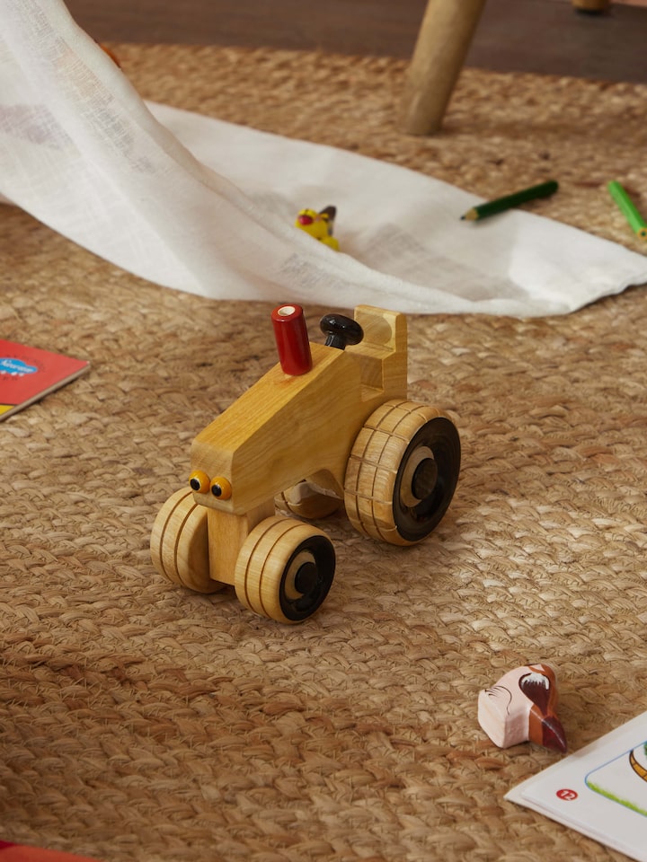 Side view of white Channapatna ivory wood tractor toy showcasing fine craftsmanship