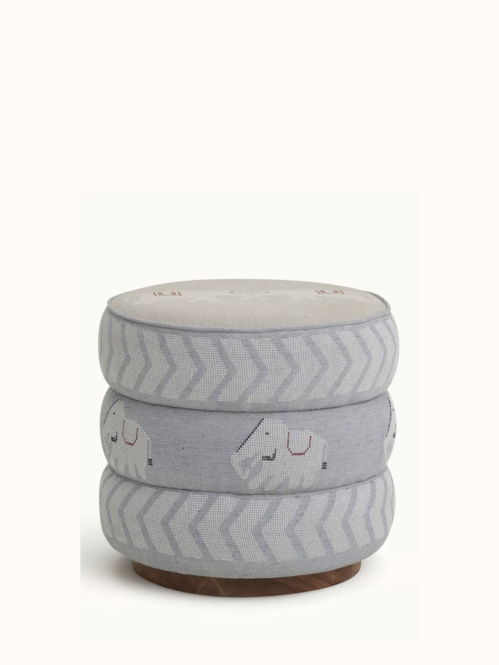 Front view of the upholstered Sheesham wood Bawan Buti pouffe, showing its detailed fabric pattern and wooden base
