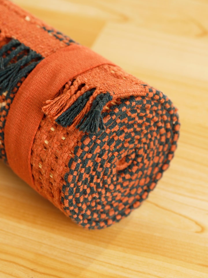 Side view of Swadesh Brown Natural Grass Cotton Yoga Mat displaying its flexibility and organic material for enhanced yoga practice.