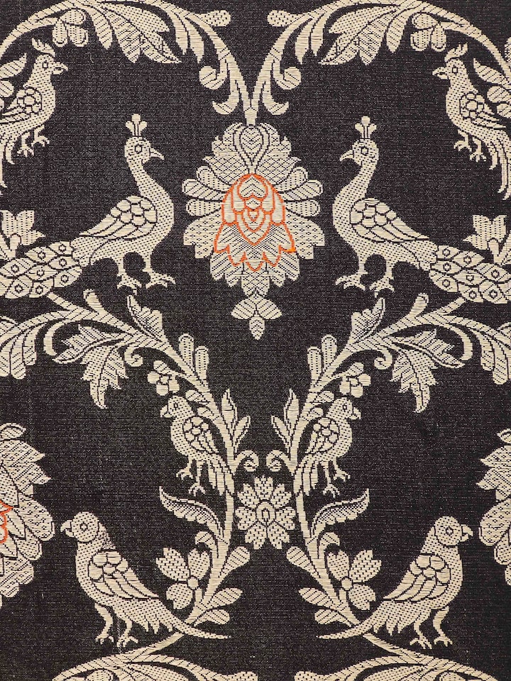 Detail shot of intricate golden jaal motifs on black silk background.