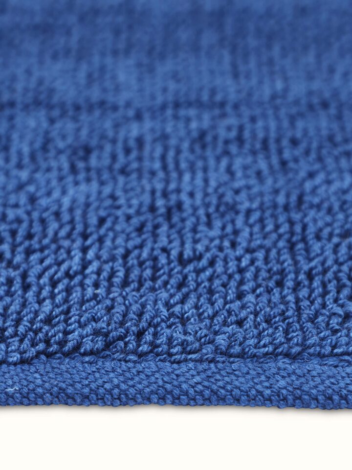 Angled view of Nityam solid blue cotton bath mat