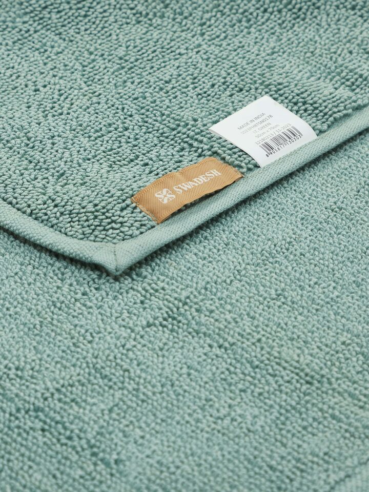Absorbent looped fabric detail of light green cotton bath mat