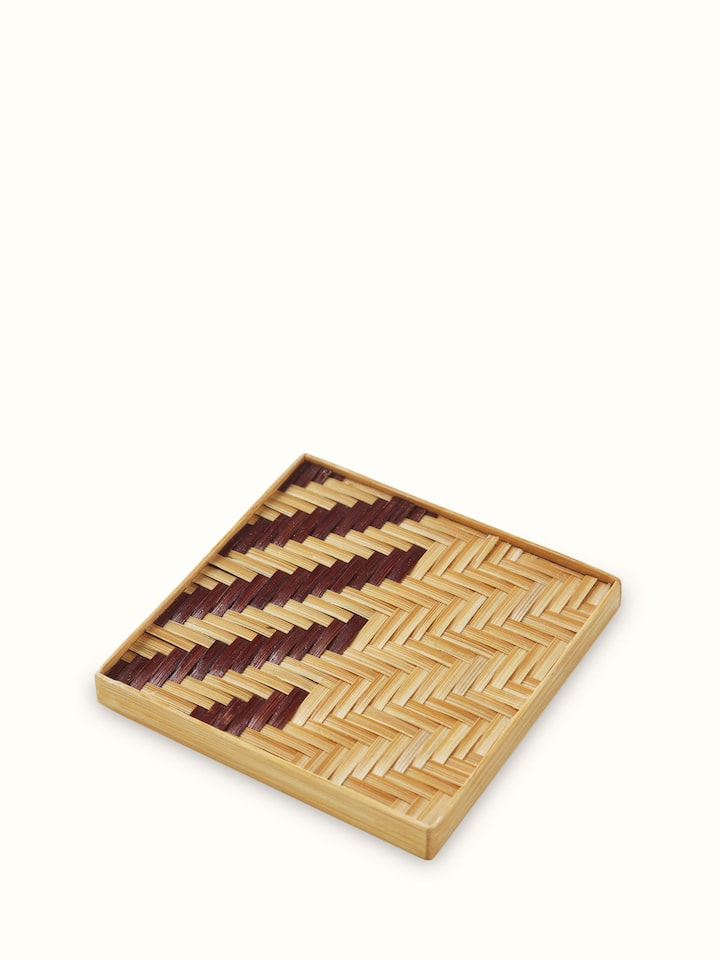 Front view of a single Naveena brown geometric bamboo coaster showing natural fibre weave and sharp edges.