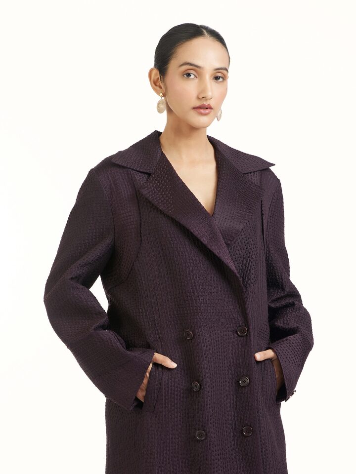 Angled view of purple silk kantha trench coat highlighting stitched patterns