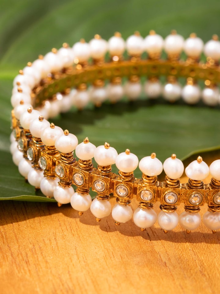 Detail shot capturing pearl clusters and engraved silver details of bangle.
