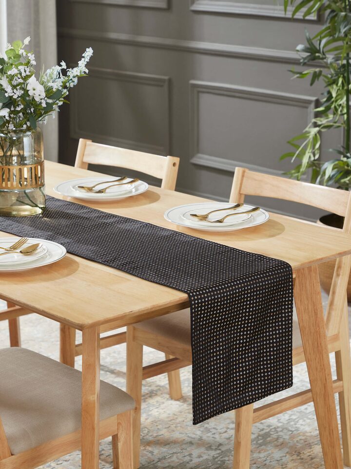 Table setting showcasing elegant Ibhan Banarasi silk runner in black and gold finish.