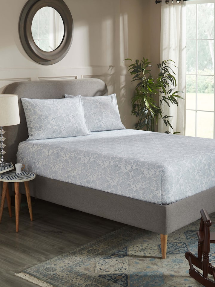 Lifestyle view: Kairavam blue floral cotton bedsheet set arranged on queen bed in bedroom setting