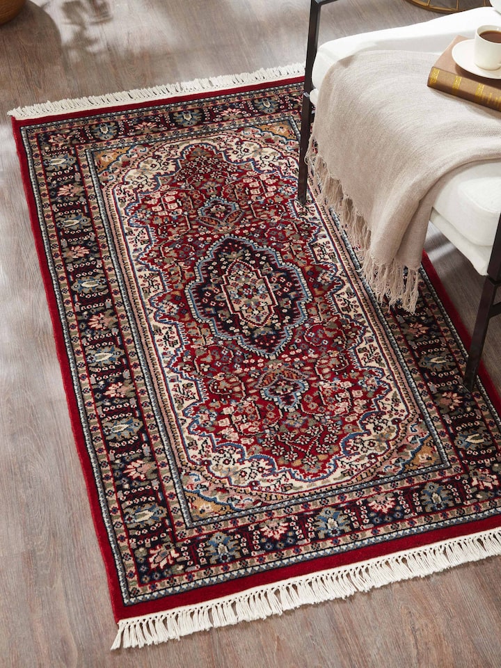 Lifestyle view of Persian red Oriental Gwalior wool hand-knotted carpet placed in a traditional living room setting.