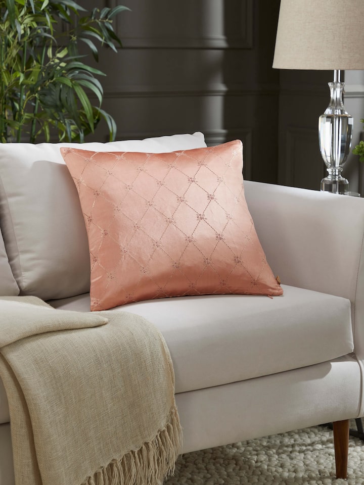 Lifestyle shot: Styled cushion in warm peach silk adding elegance to upholstered seating.