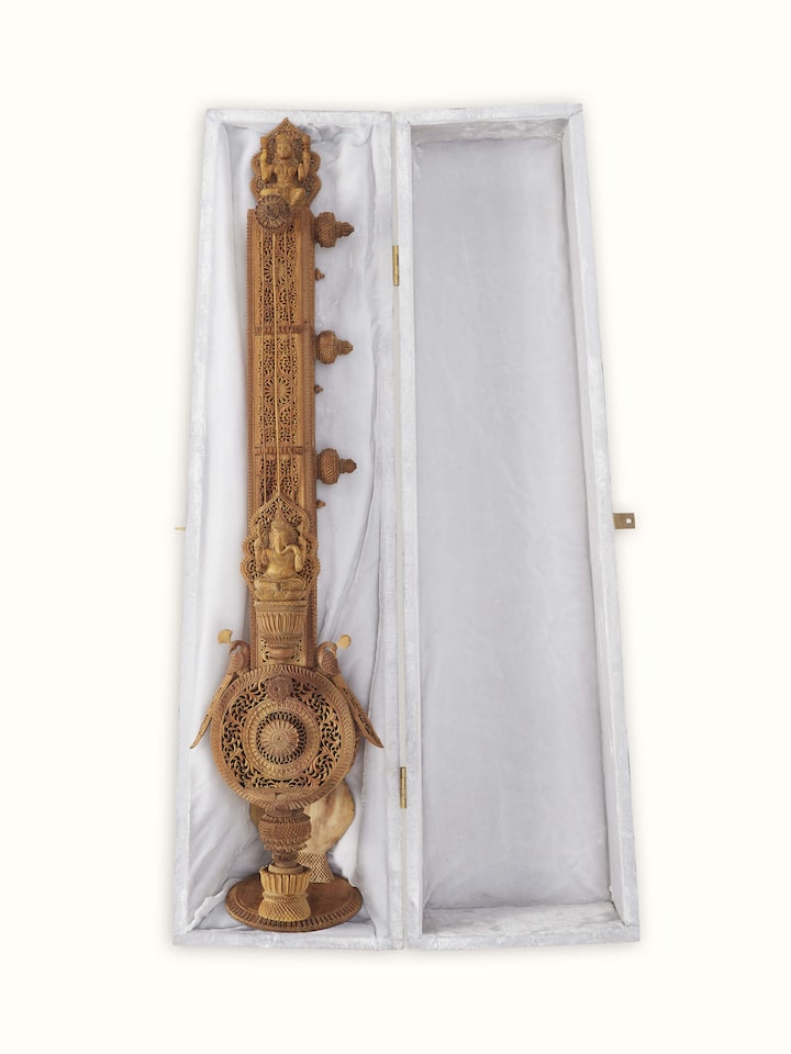 Close-up of carved sandalwood veena sculpture, focusing on the delicate carvings and smooth finish.