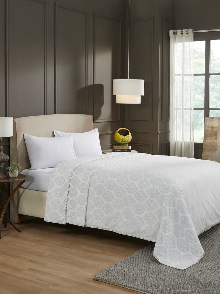 Lifestyle view of Mihrab Grey Ogee Cotton Sanganeri Hand Block Print Double Dohar draped on bed, showcasing traditional floral pattern and soft texture.