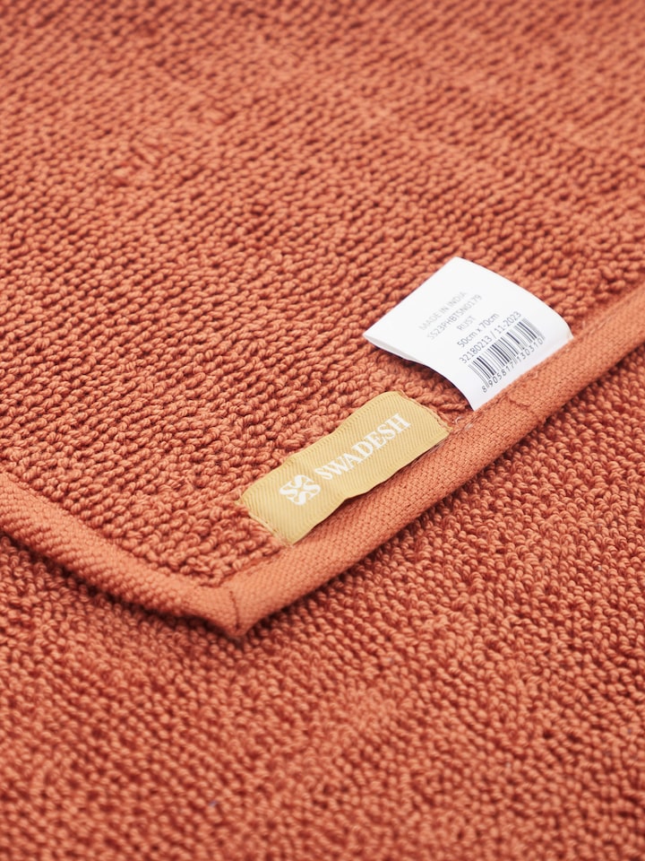 Absorbent looped fabric detail of rust cotton bath mat