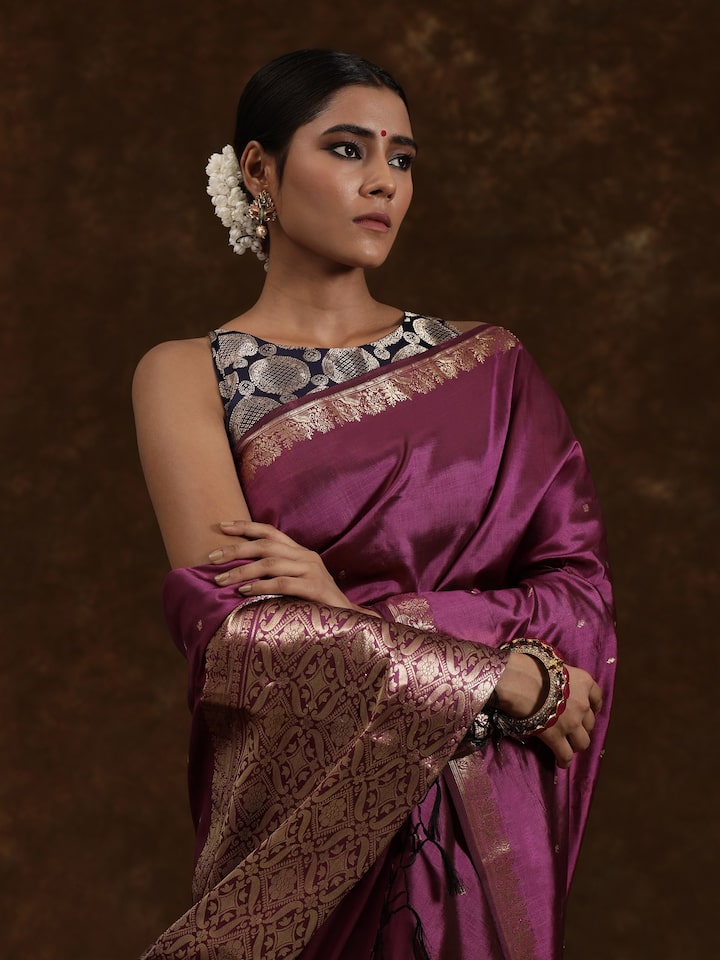 Close-up of Banarasi saree revealing fine zari weave on purple silk base.