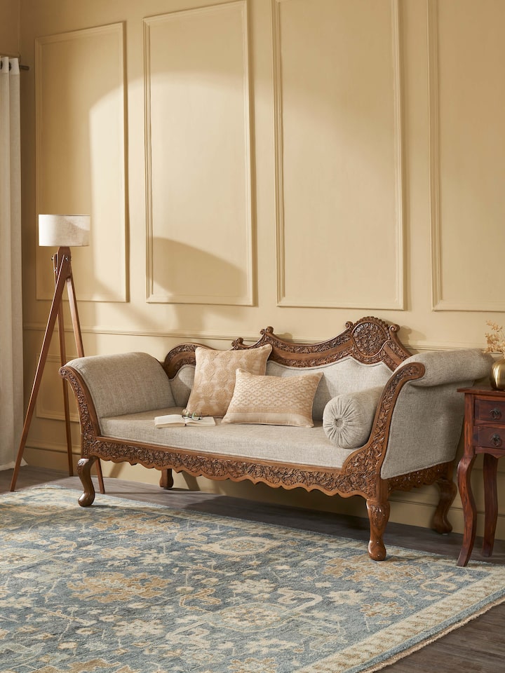 Side view of the handloom fabric upholstered carved walnut wood daybed, highlighting the daybed’s elegant profile and carving details