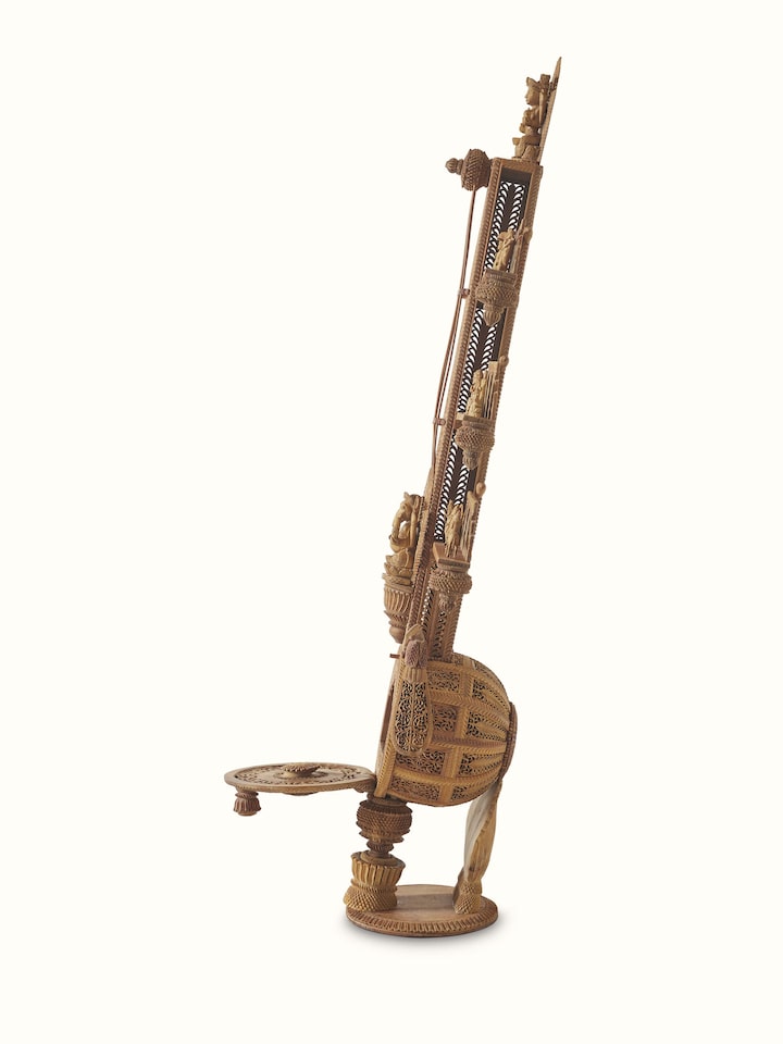 Carved sandalwood veena sculpture with detailed close-up, emphasizing the intricate artistry of the piece.