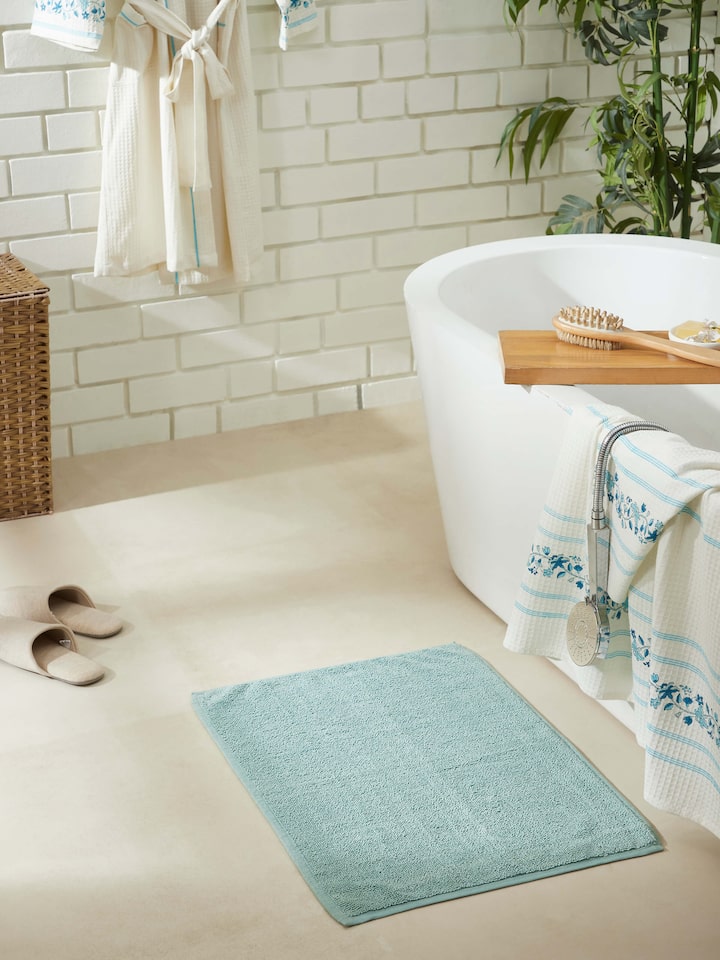Light green cotton bath mat placed in bathroom setting