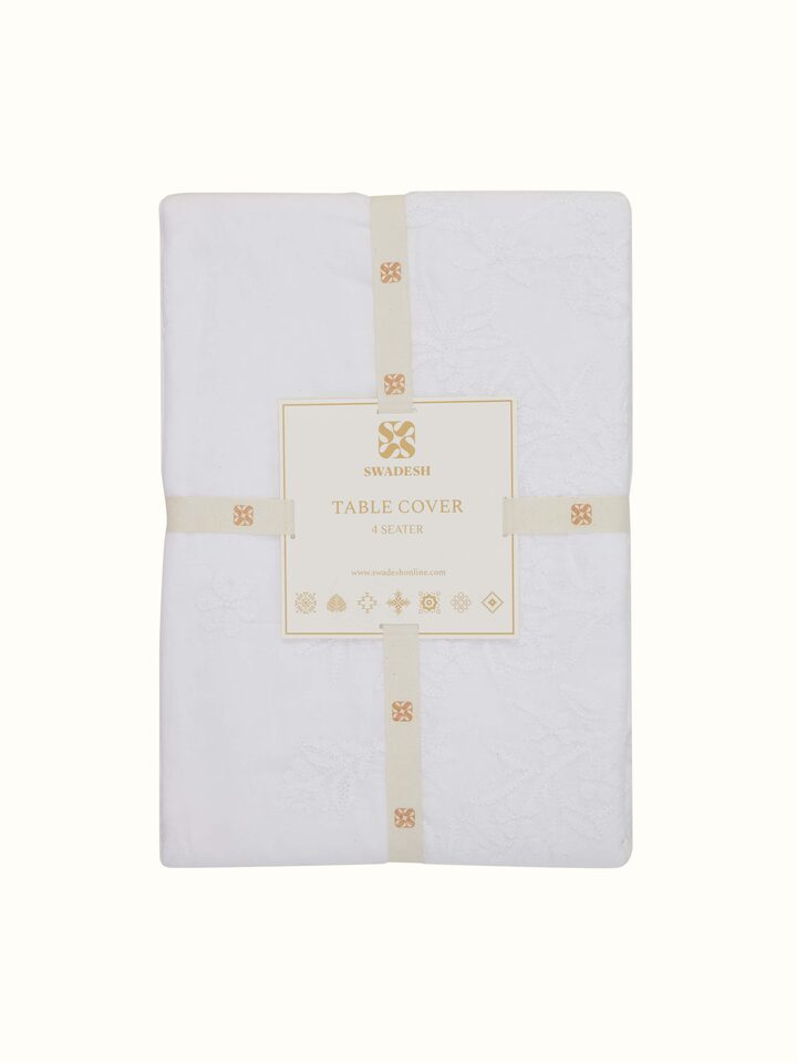 Close-up of Ananda white Chikankari table cover showing medallion embroidery and delicate cotton texture.