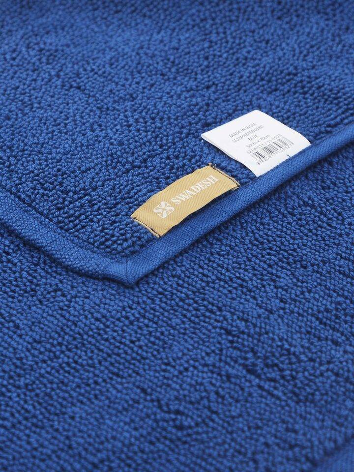 Absorbent looped fabric detail of blue cotton bath mat