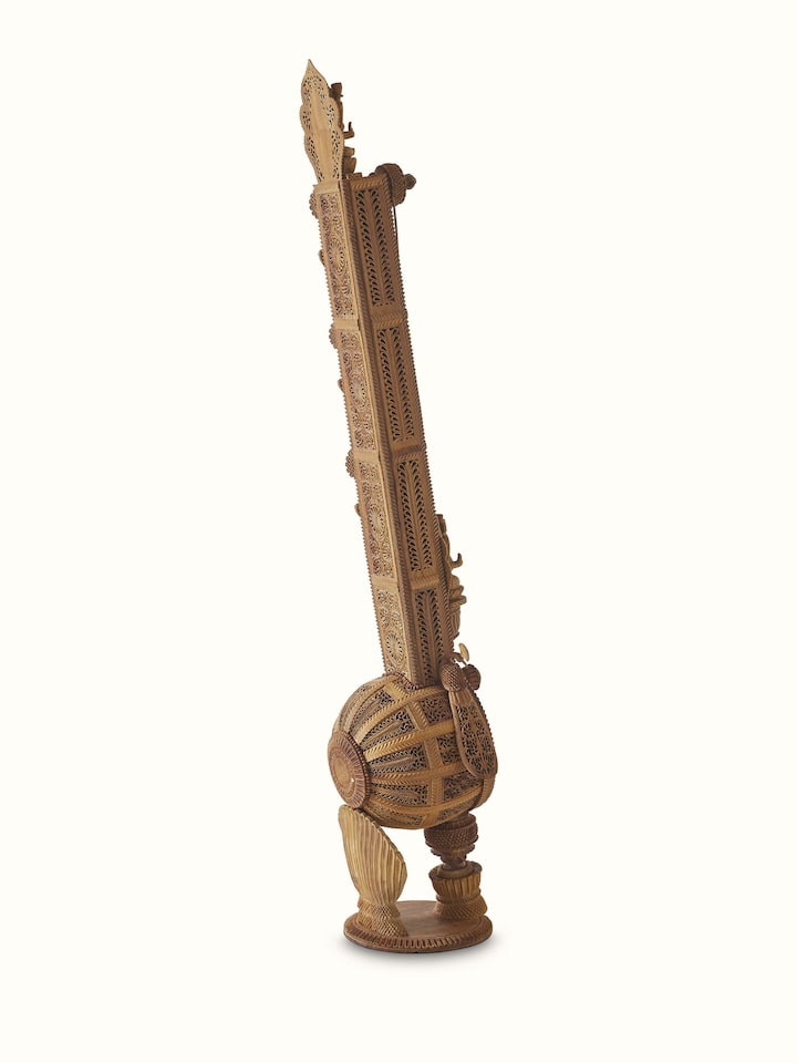 Close-up of carved sandalwood veena sculpture, highlighting the smooth texture and detailed craftsmanship.
