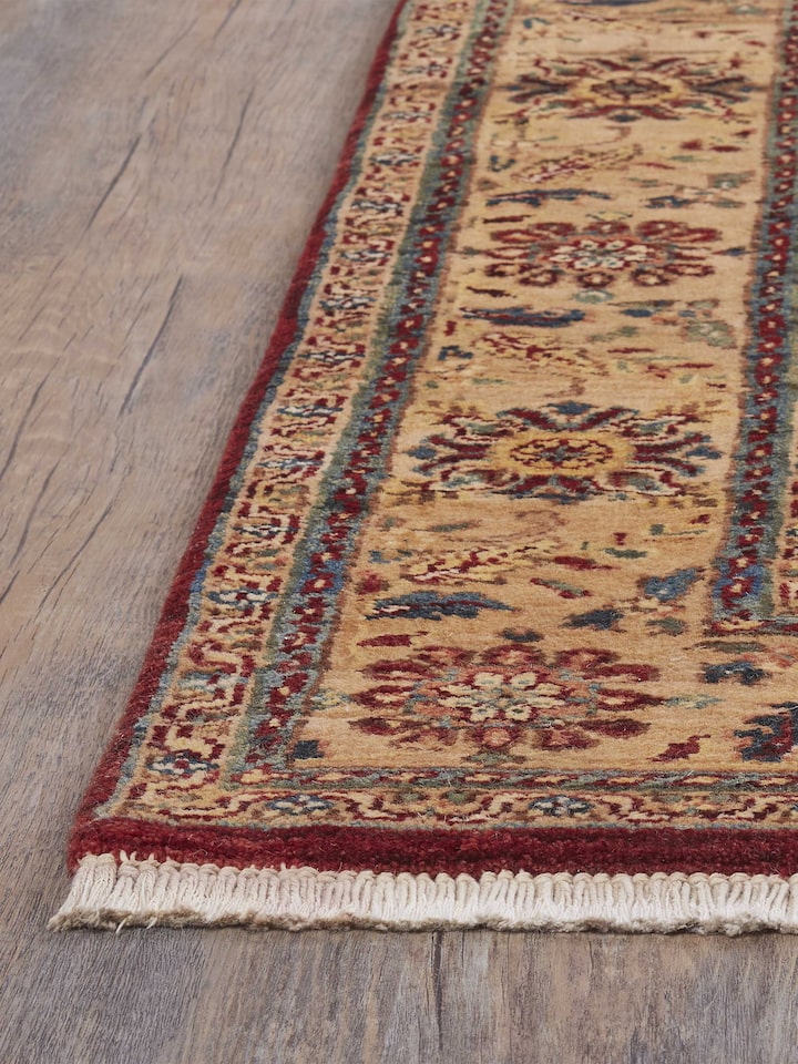 Angled view of traditional gold Ziegler Jaipur hand-knotted wool rug with ornate motifs